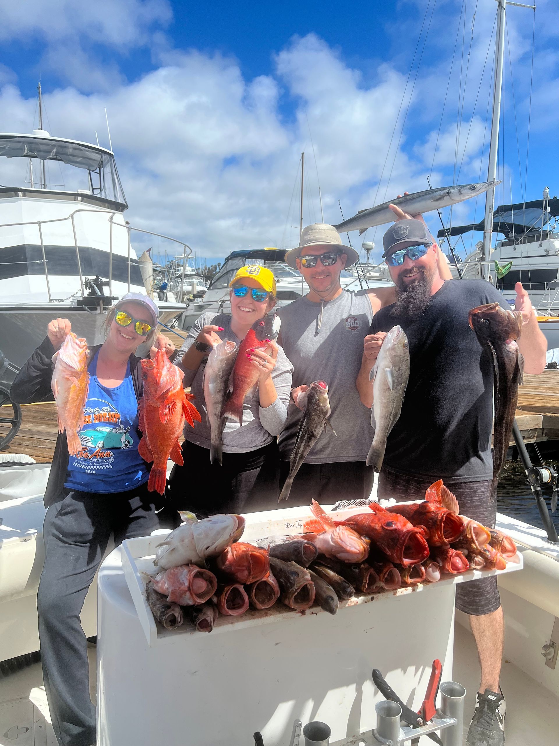 A group of people are standing on a boat holding fish.