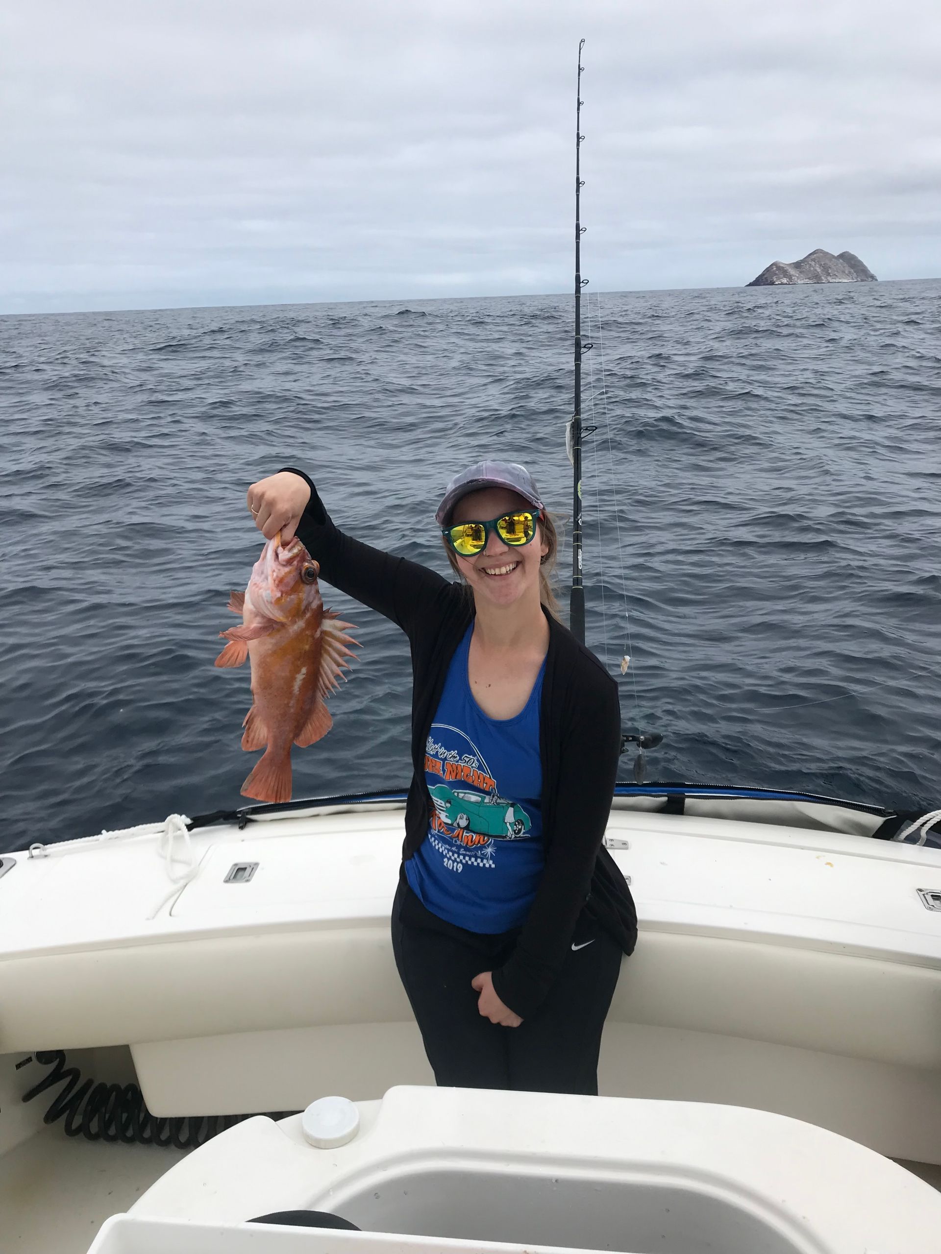 A woman is holding a fish on a boat in the ocean