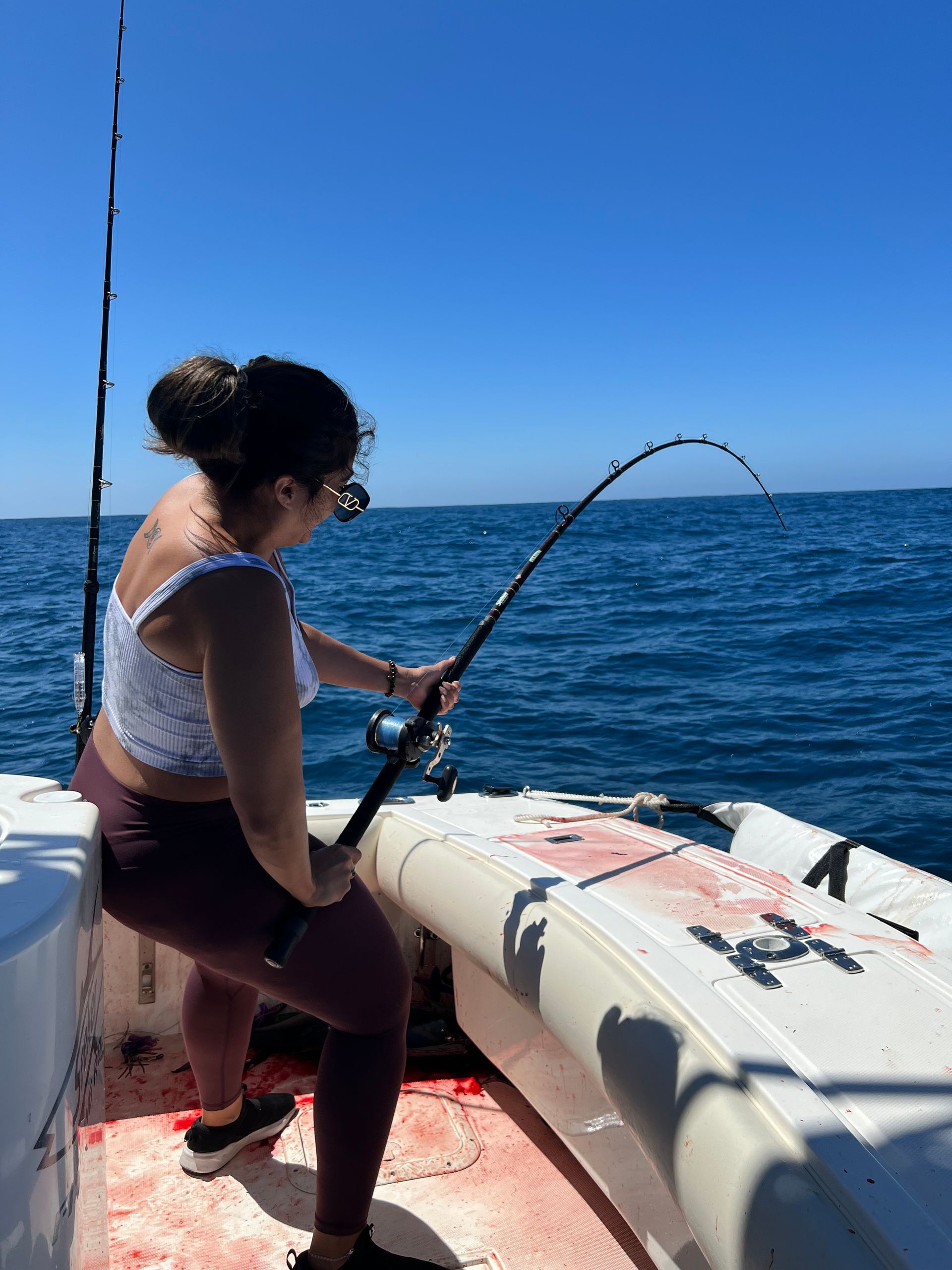 A woman is fishing on a boat in the ocean.