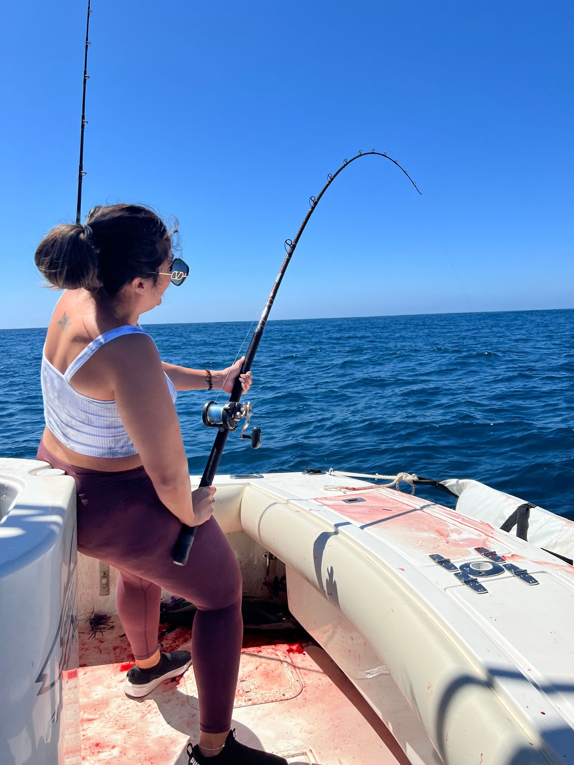 A woman is fishing on a boat in the ocean.