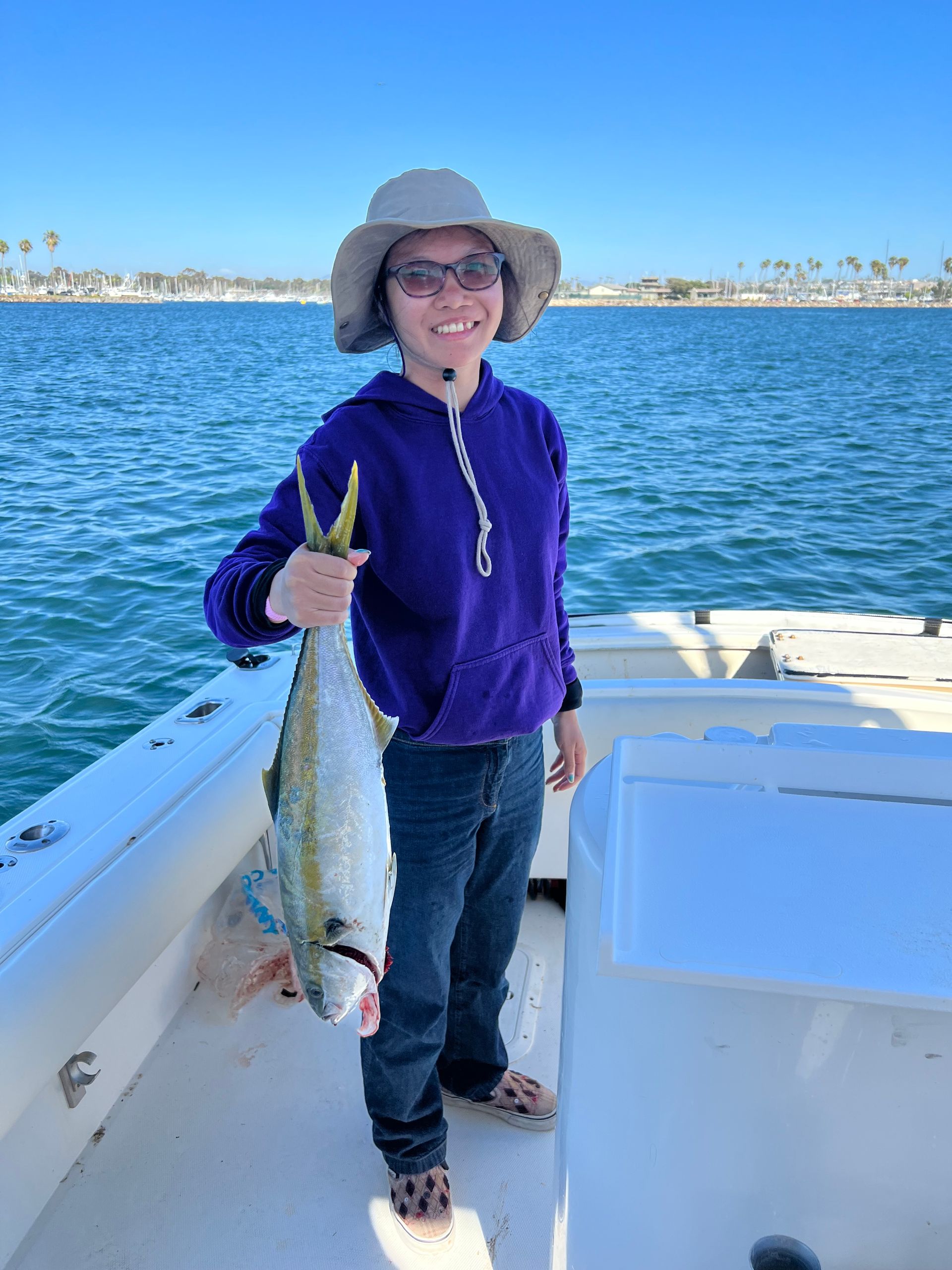 A woman is holding a large fish on a boat.