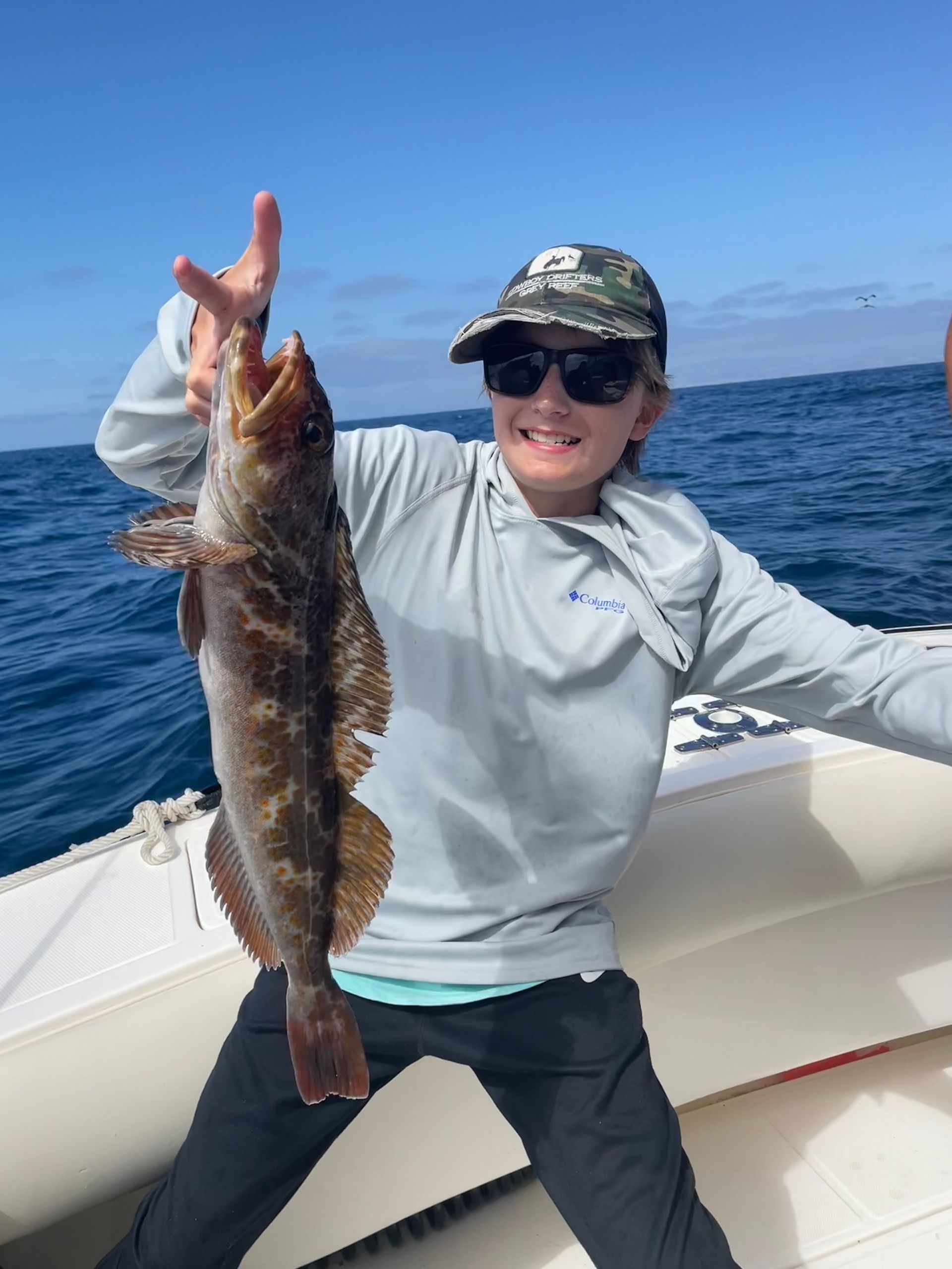 A woman is holding a fish on a boat in the ocean.