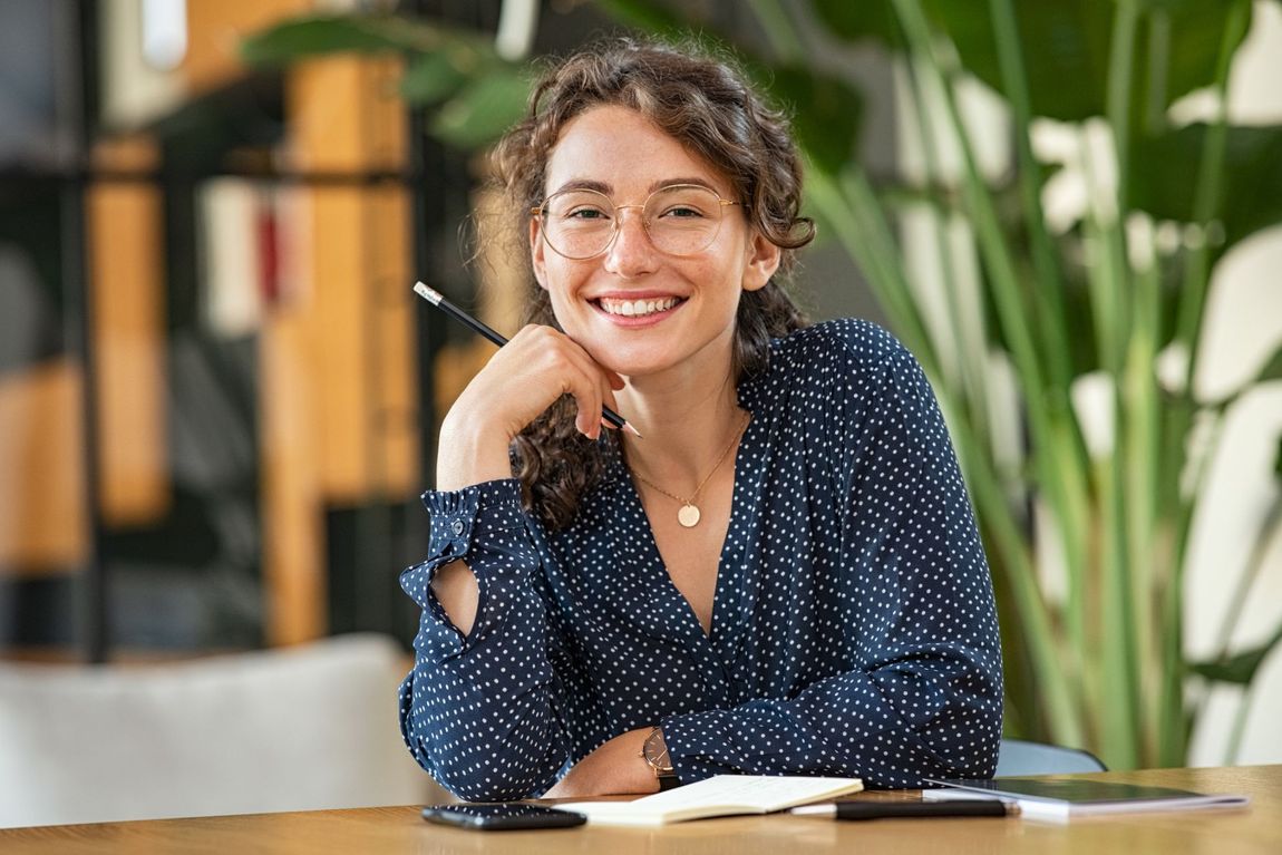 Giovane ragazza sorridente seduta su una scrivania