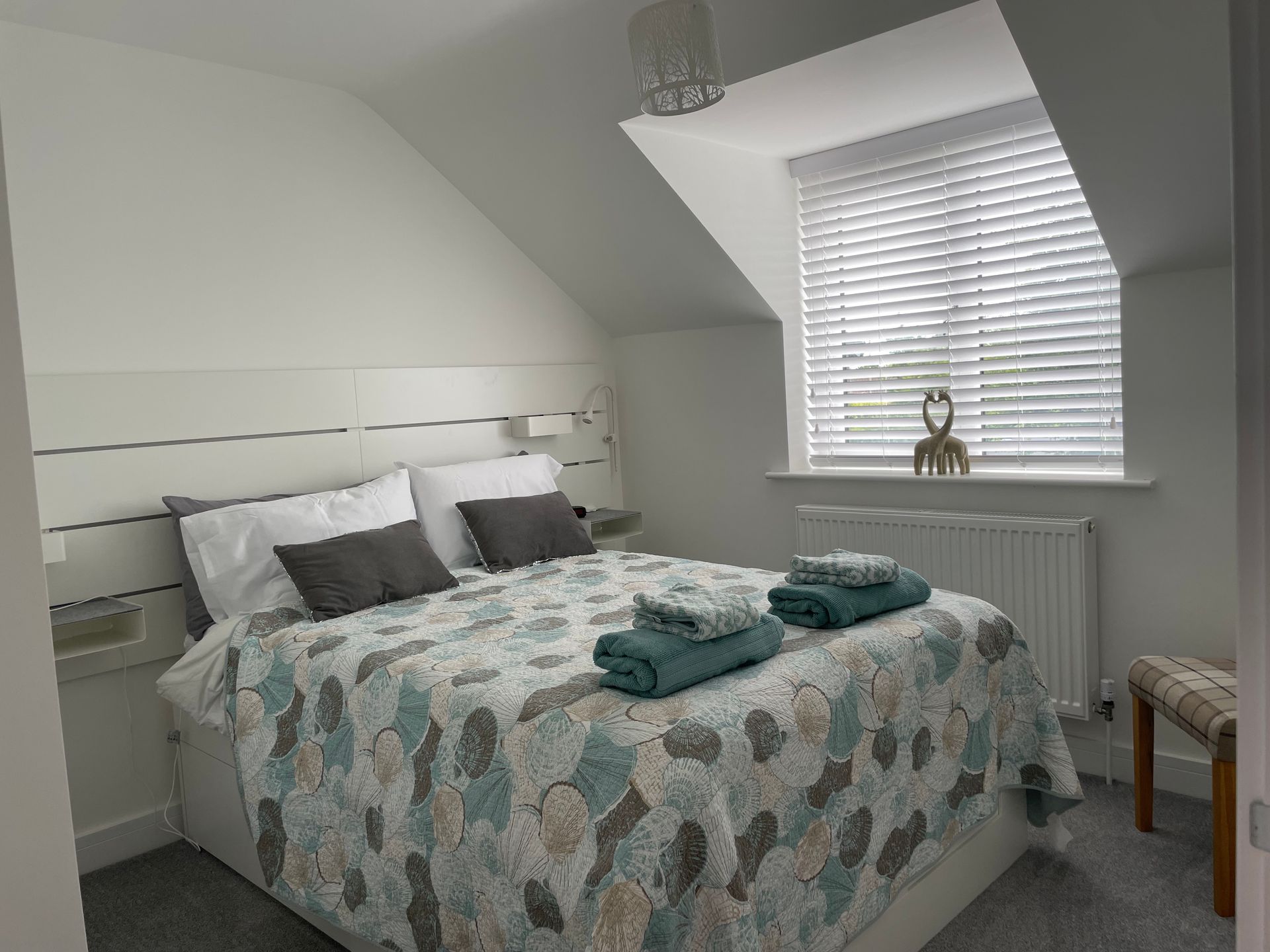 A bedroom with a bed and a window with blinds.