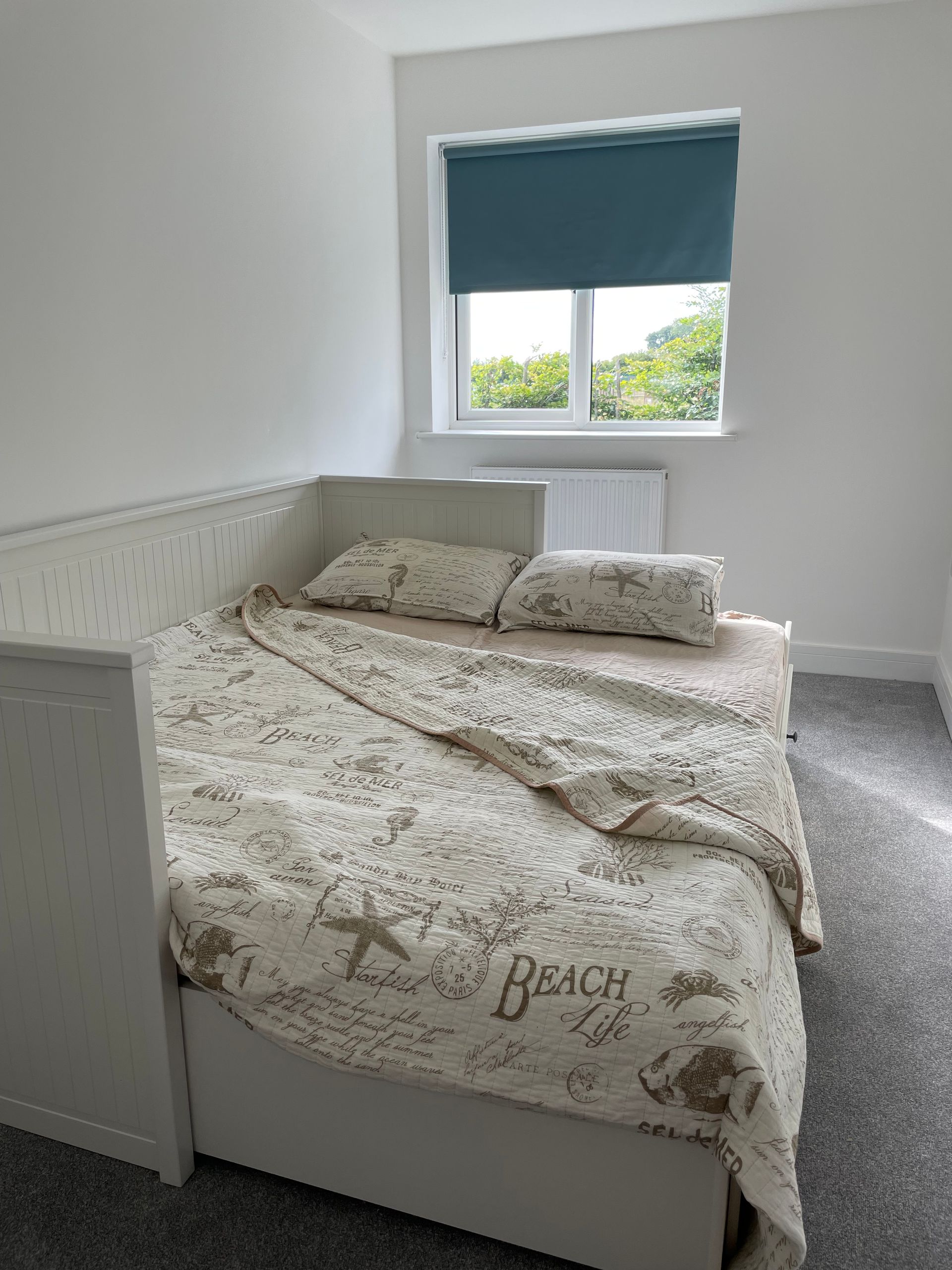 A bedroom with a bed and a window with a blue blind.