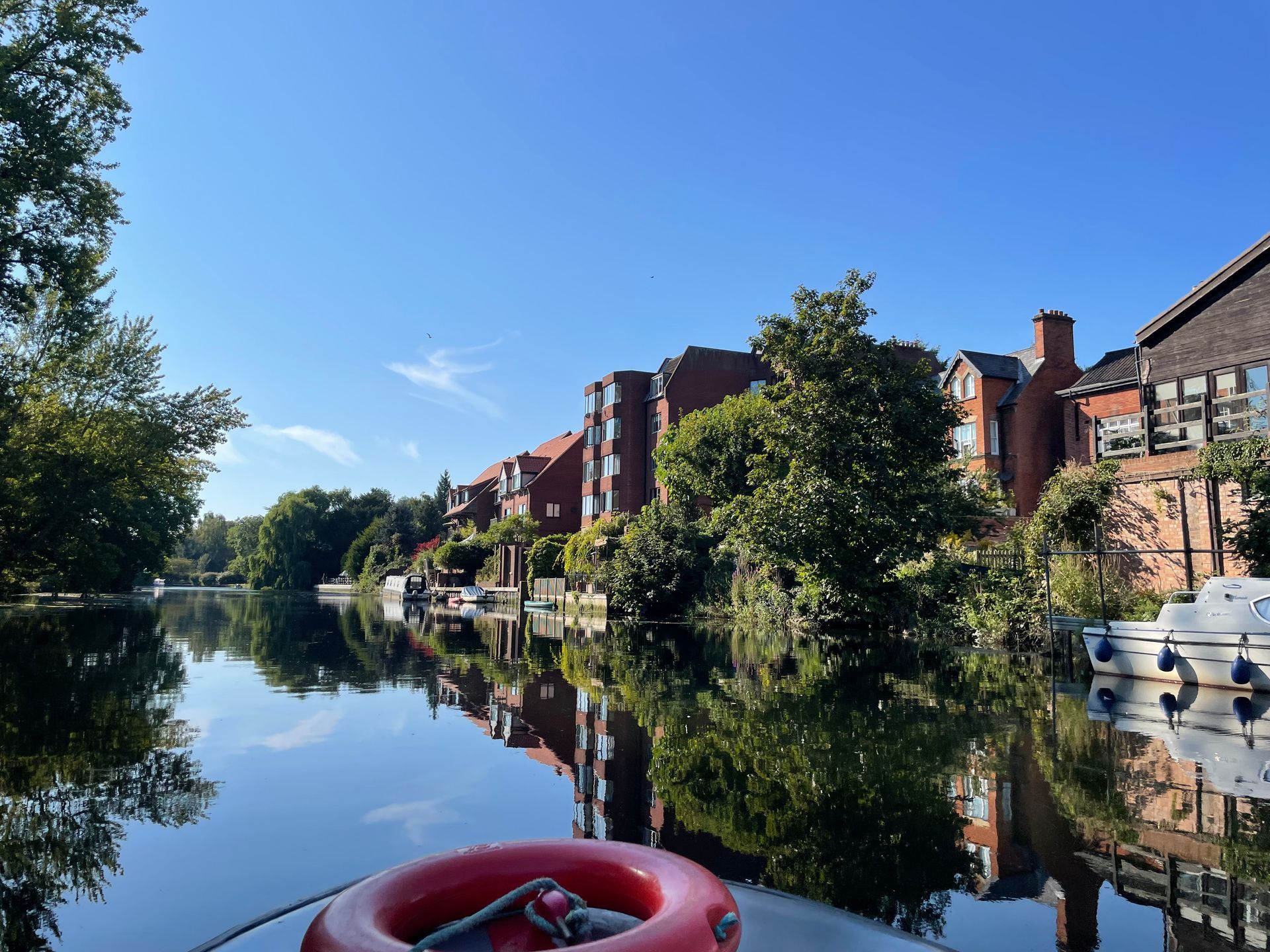 A red life preserver is floating on a river with buildings in the background