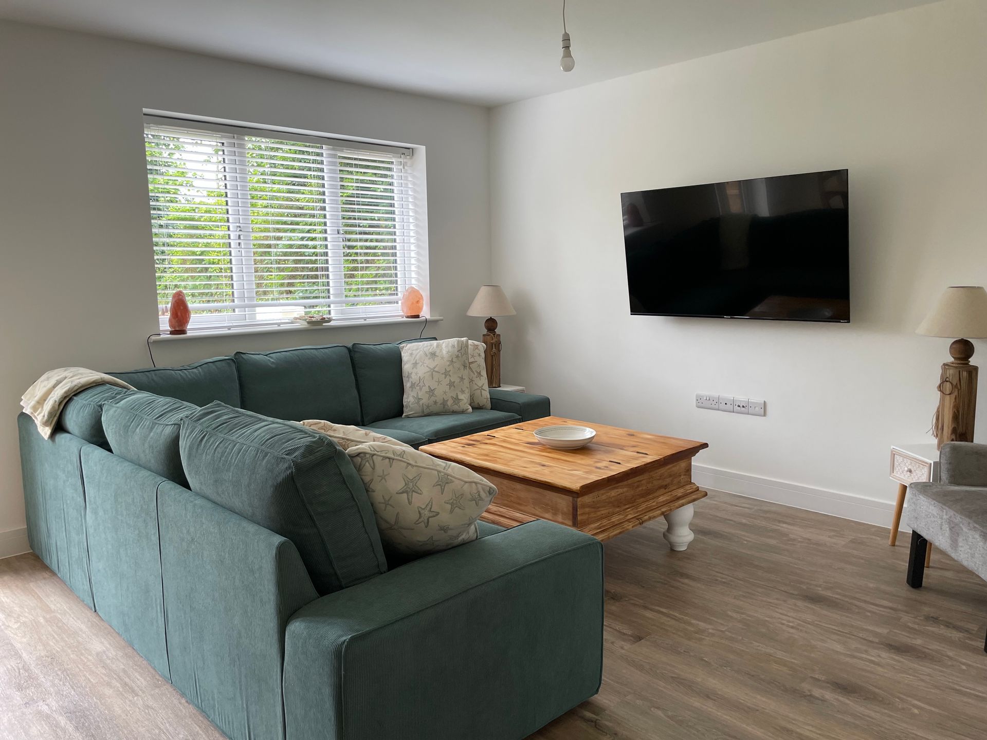 A living room with a couch , coffee table , and flat screen tv.