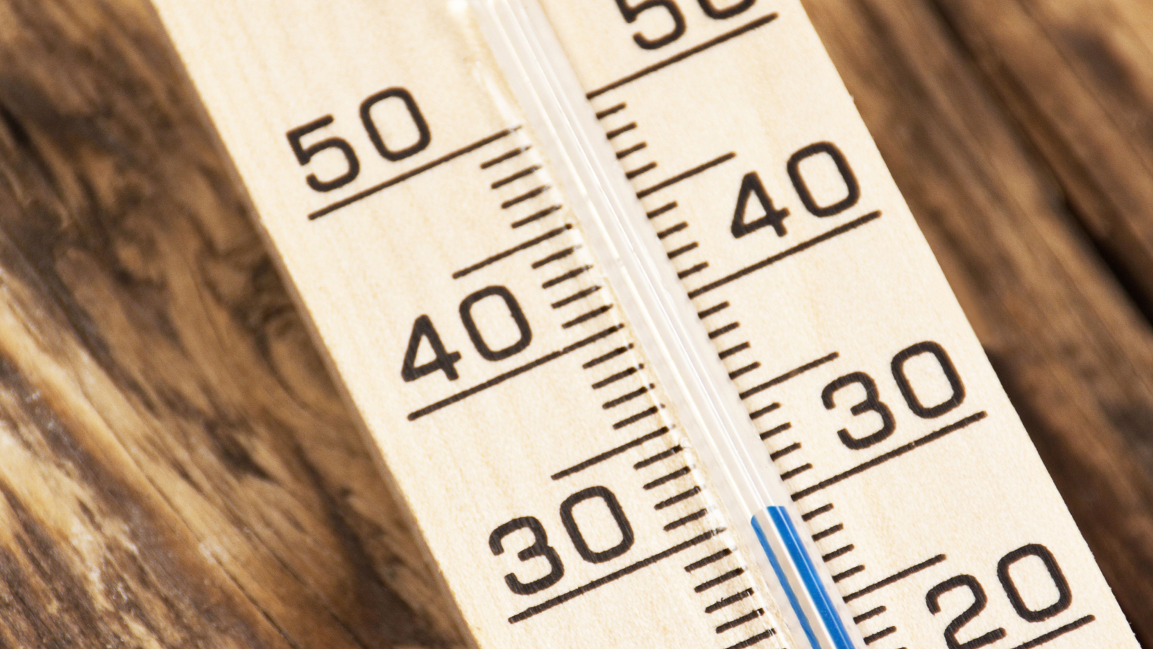 Close-up of a thermometer showing around 30°F to 50°F on a wooden surface