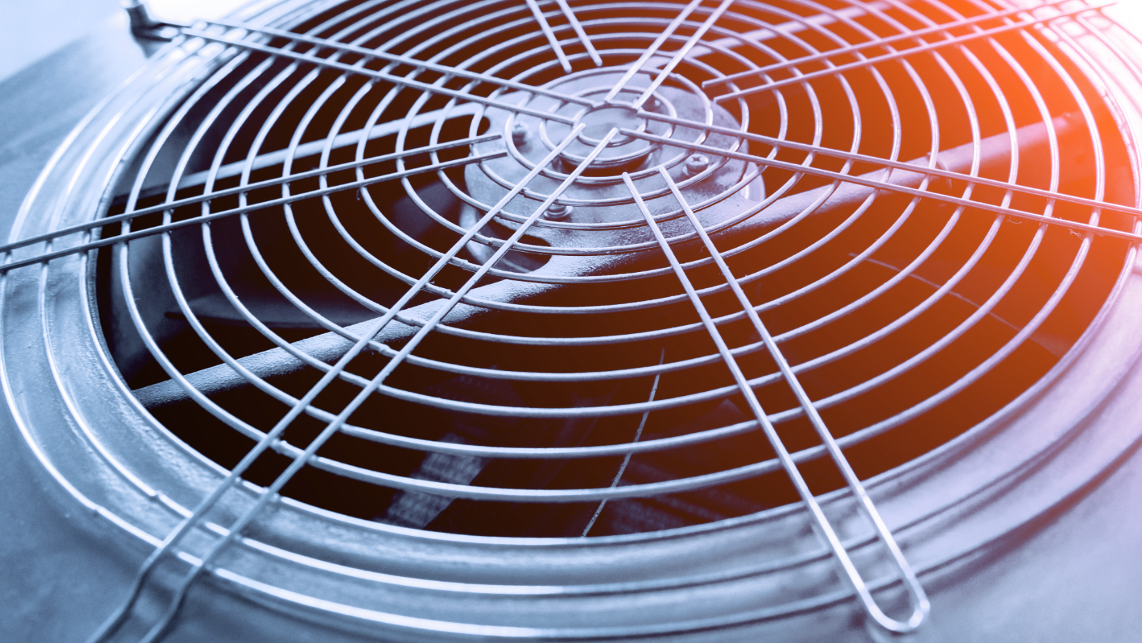 Close-up of a metal fan grille with blades glowing red and blue from reflected light