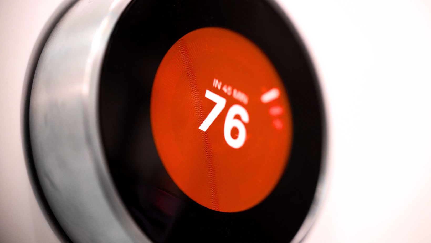 Close-up of a black circular dial showing 76 on an orange-red display