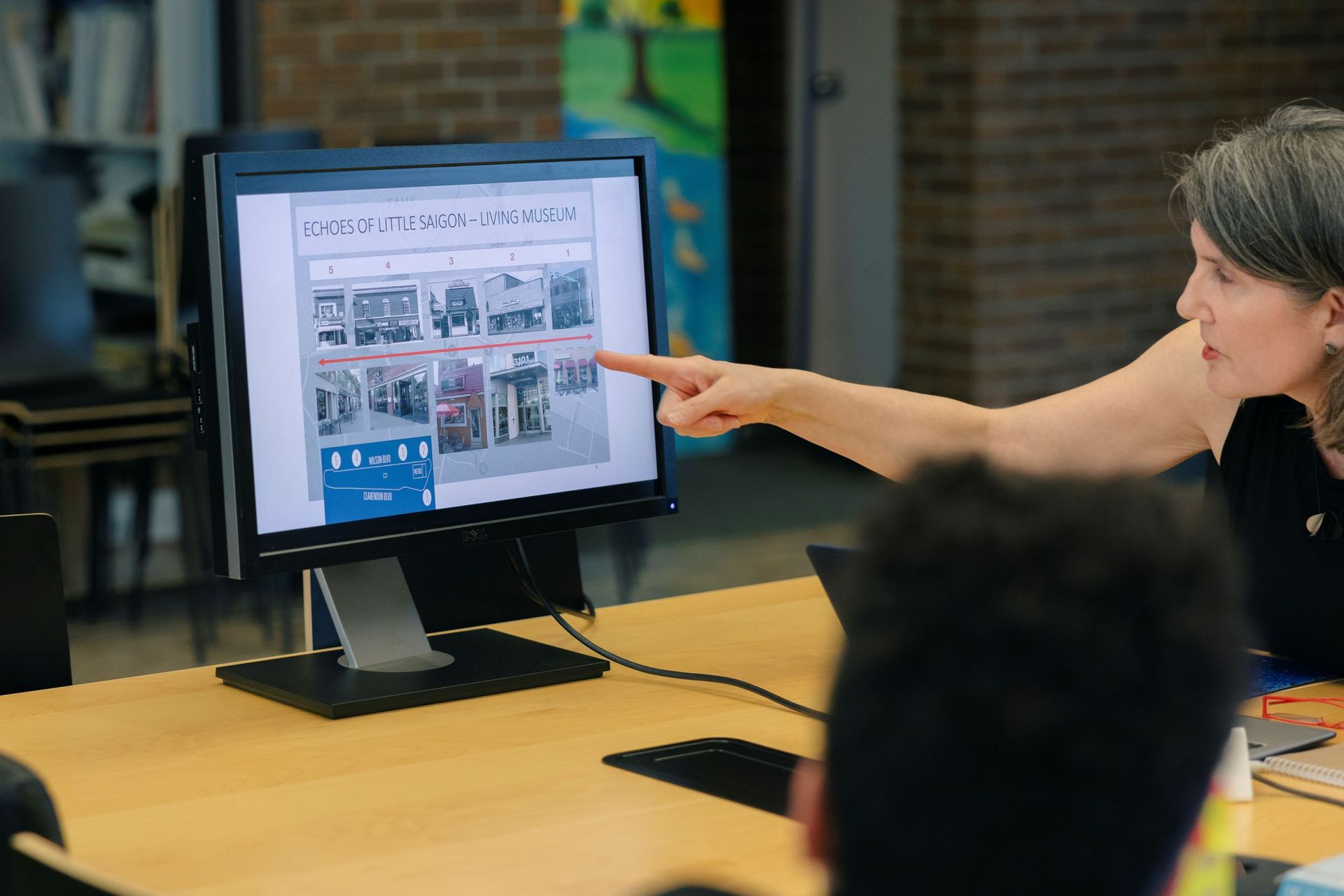 Woman pointing at a desktop monitor during a meeting in an office