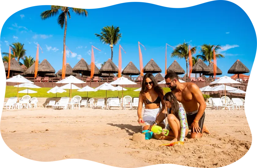 Uma família está brincando na areia de uma praia.