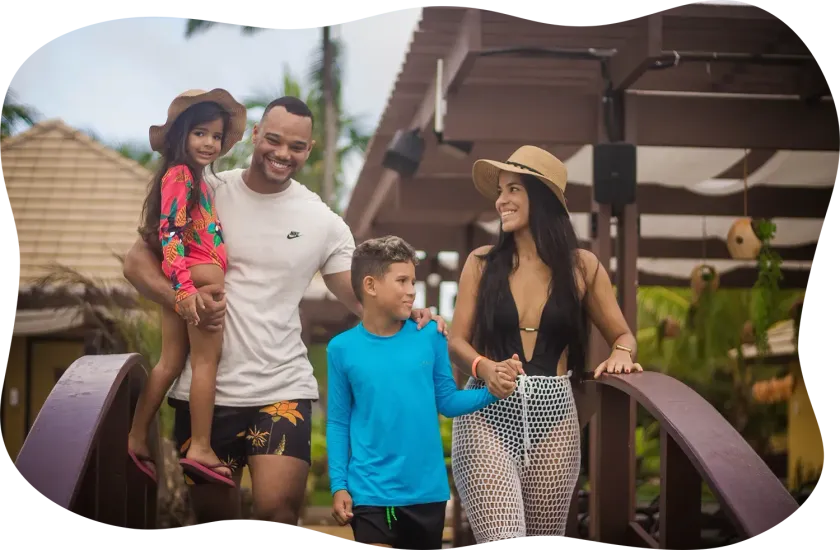 Uma família está de pé em uma ponte de mãos dadas e sorrindo.