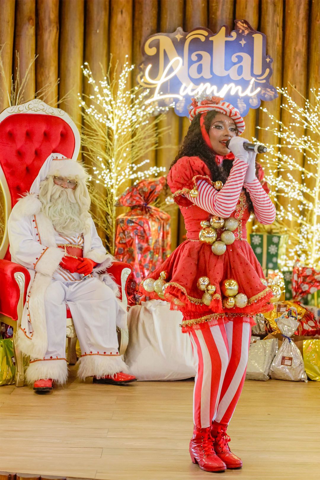 Uma mulher está tirando uma foto do Papai Noel no palco
