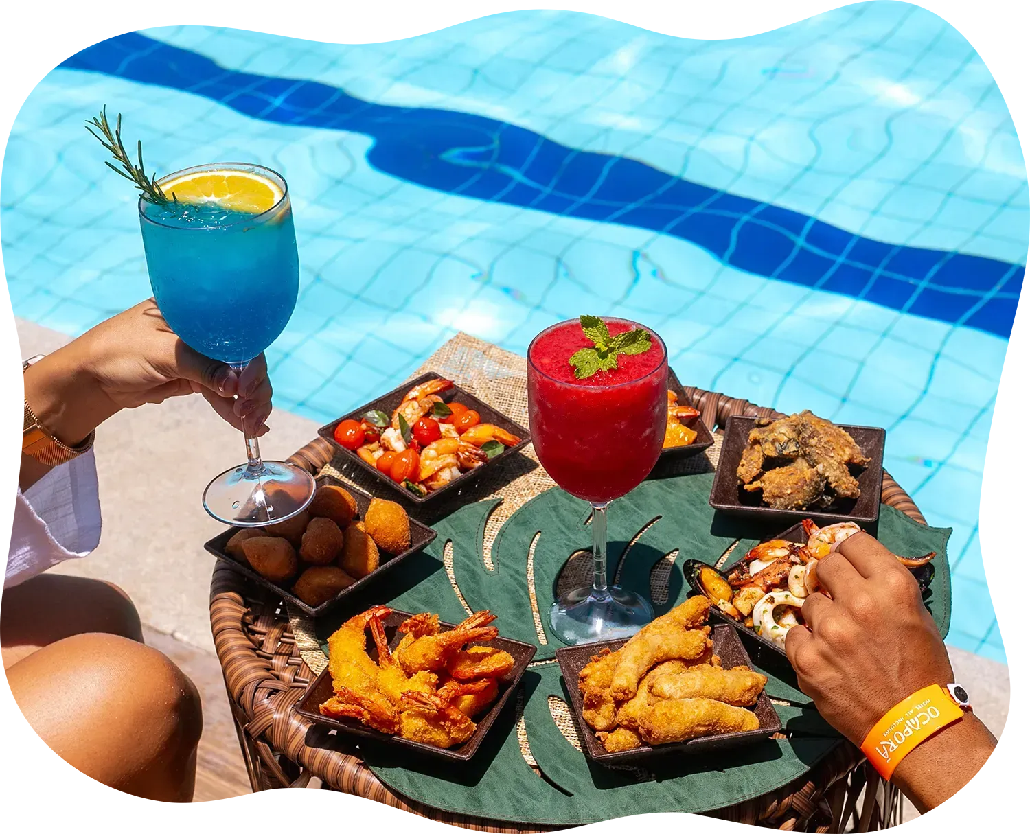 Uma pessoa está sentada perto de uma piscina com uma bandeja de comida e bebidas.