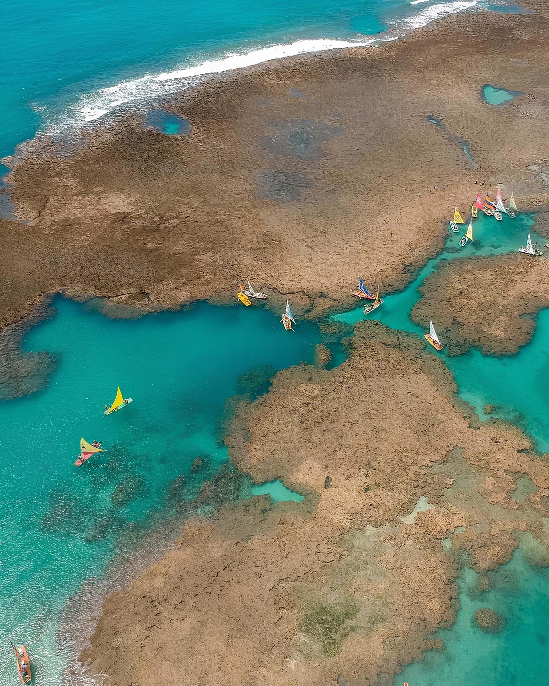 Uma vista aérea de um recife de coral no oceano com barcos na água.