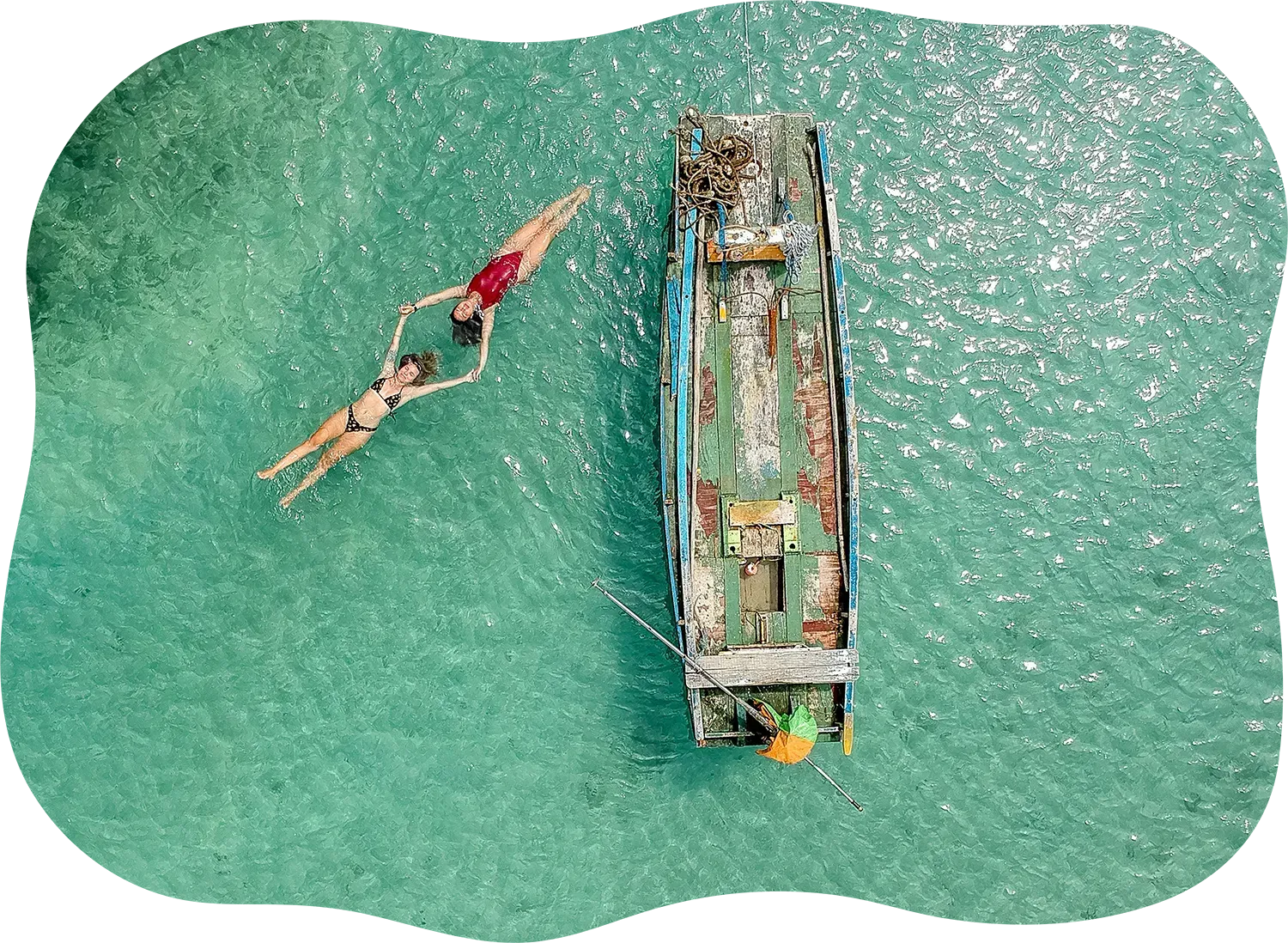 Uma vista aérea de duas pessoas nadando no oceano ao lado de um barco.