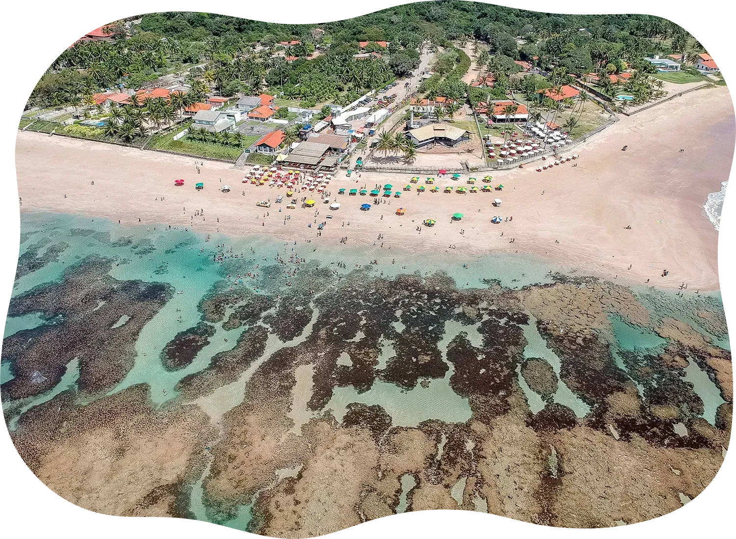 Uma vista aérea de uma praia com muitas pessoas e um recife de corais.