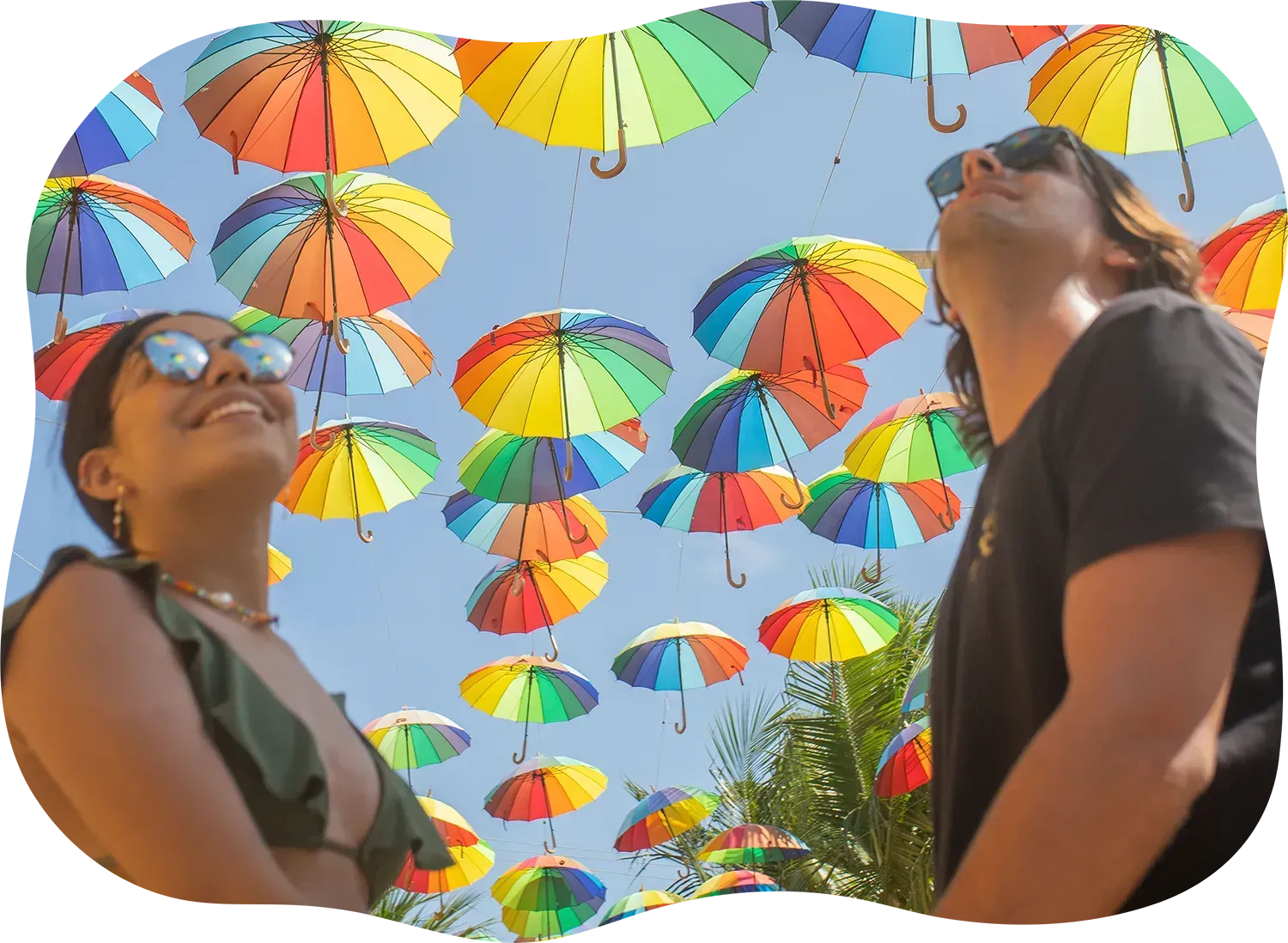 Um homem e uma mulher estão olhando para guarda-chuvas coloridos pendurados no céu