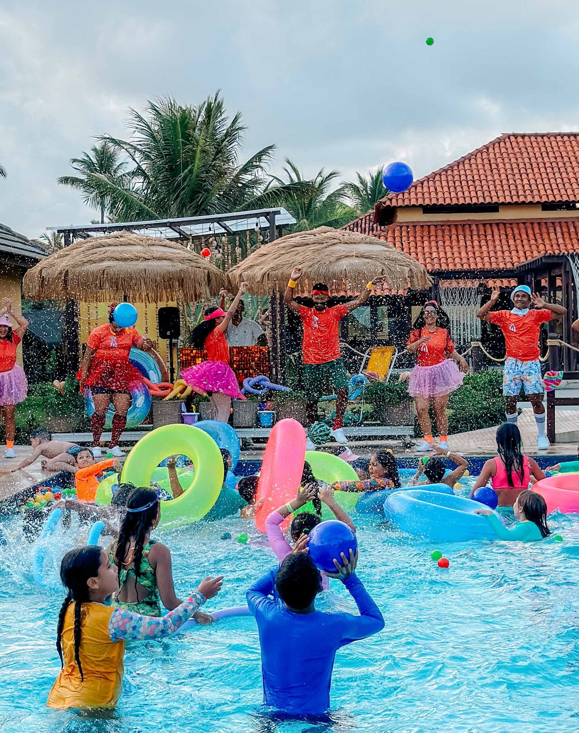 Um grupo de pessoas usando chapéus de Papai Noel estão posando para uma foto em frente a uma piscina.