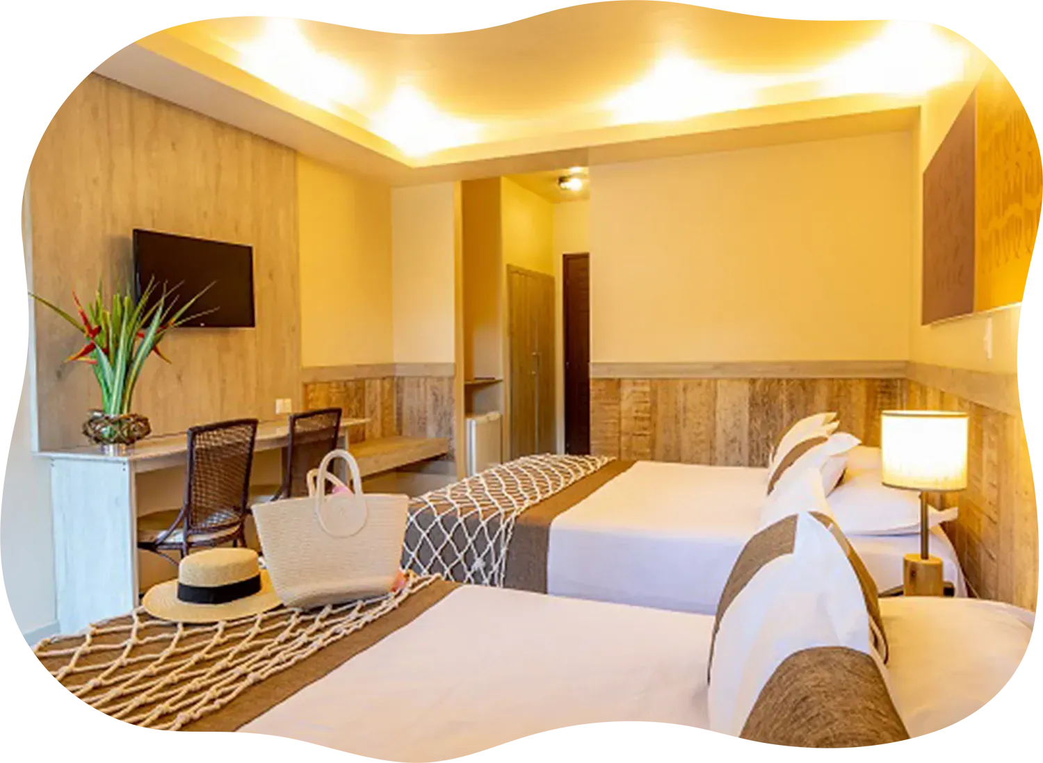 Um quarto de hotel com duas camas, uma escrivaninha e uma televisão.