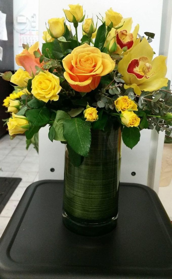 A Vase Filled With Yellow Roses and Orchids is Sitting on a Table — The Flower Station Townsville In Kirwan, QLD