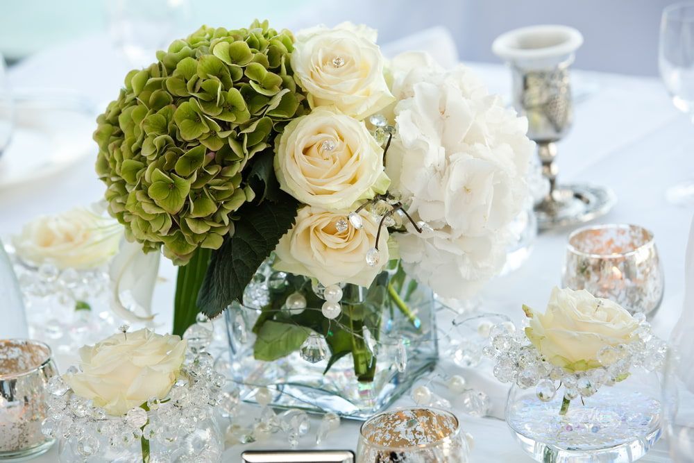 A Vase Filled With White Roses and Green Hydrangea is on a Table — The Flower Station Townsville In Kirwan, QLD A Vase Filled With White Roses and Green Hydrangea is on a Table — The Flower Station Townsville In Kirwan, QLD