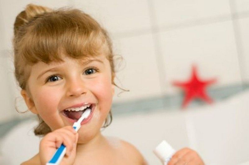Child brushing teeth in a bathroom, smiling with a red star in the background