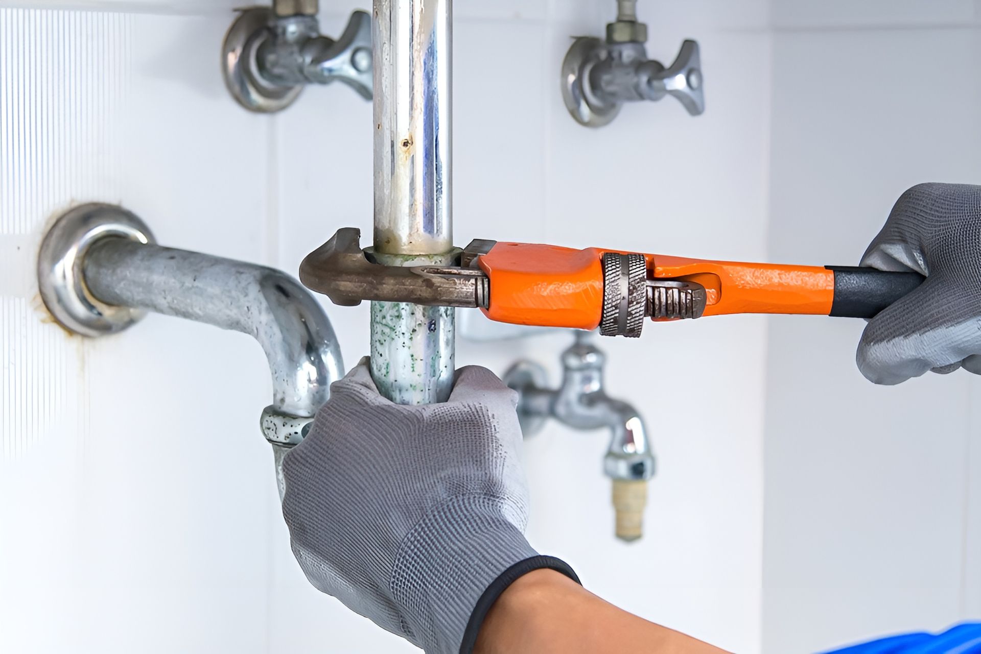 Gloved Hands Using an Orange Pipe Wrench — New Gen Plumbing and Gas in Coolangatta, NSW
