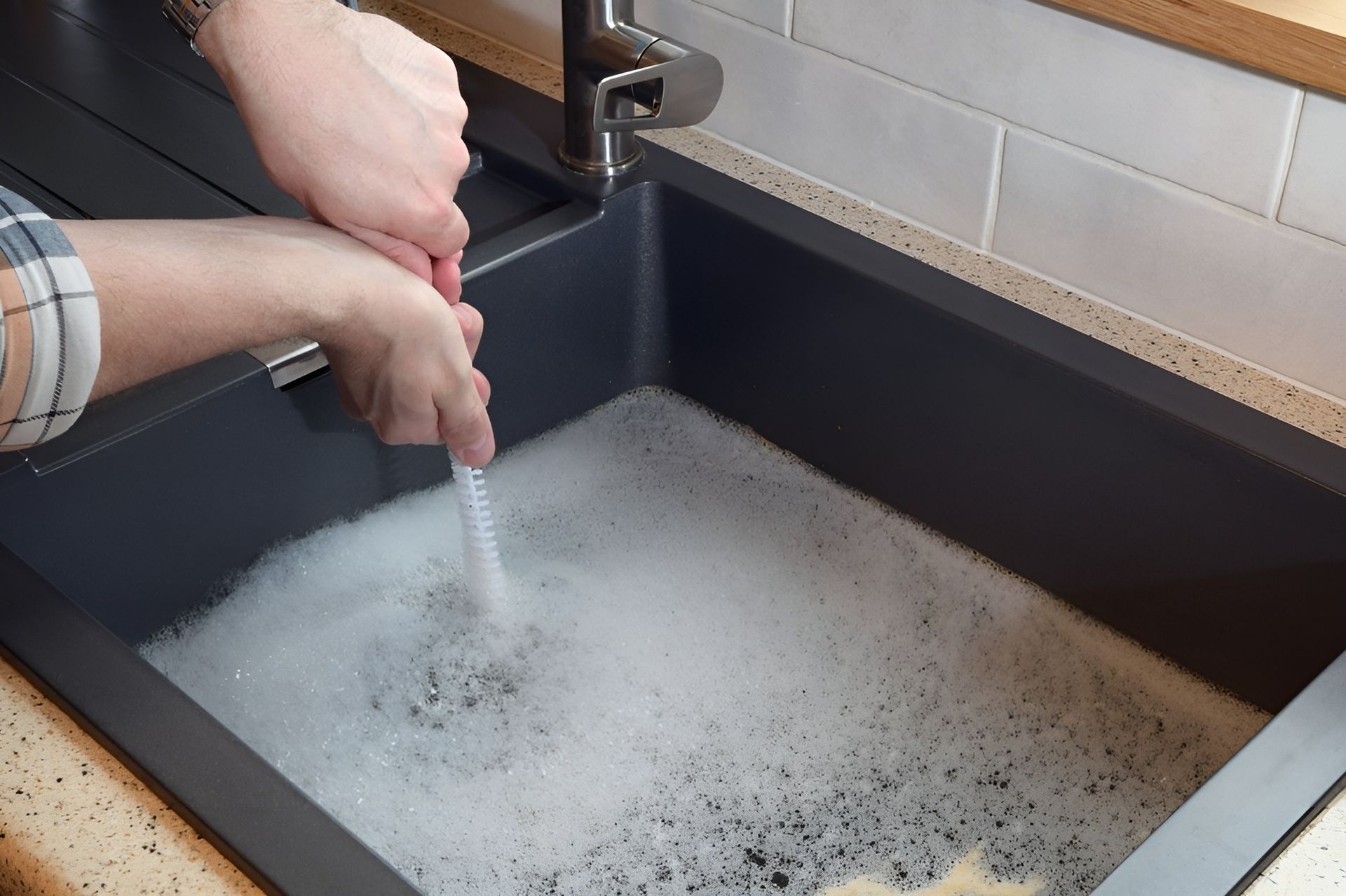 Hands rinsing dishes in a dark kitchen sink filled with soapy water — New Gen Plumbing and Gas in Kingscliff, NSW