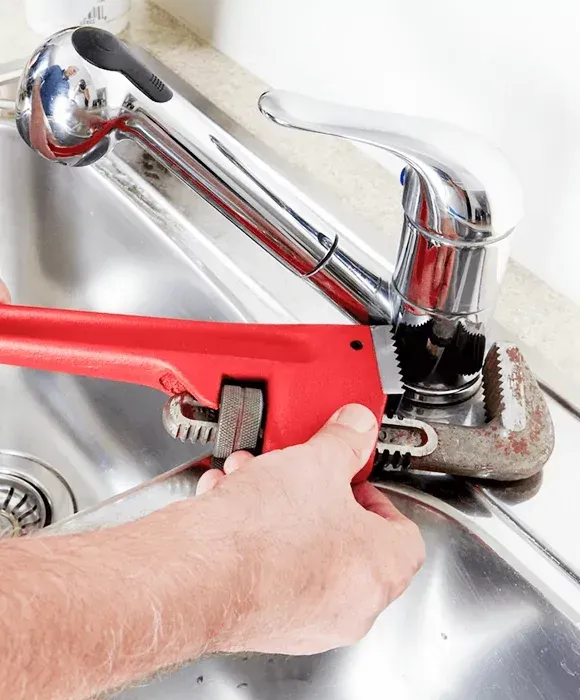 Hand tightening a chrome sink faucet pipe with a red pipe wrench — New Gen Plumbing and Gas in Banora Point, NSW