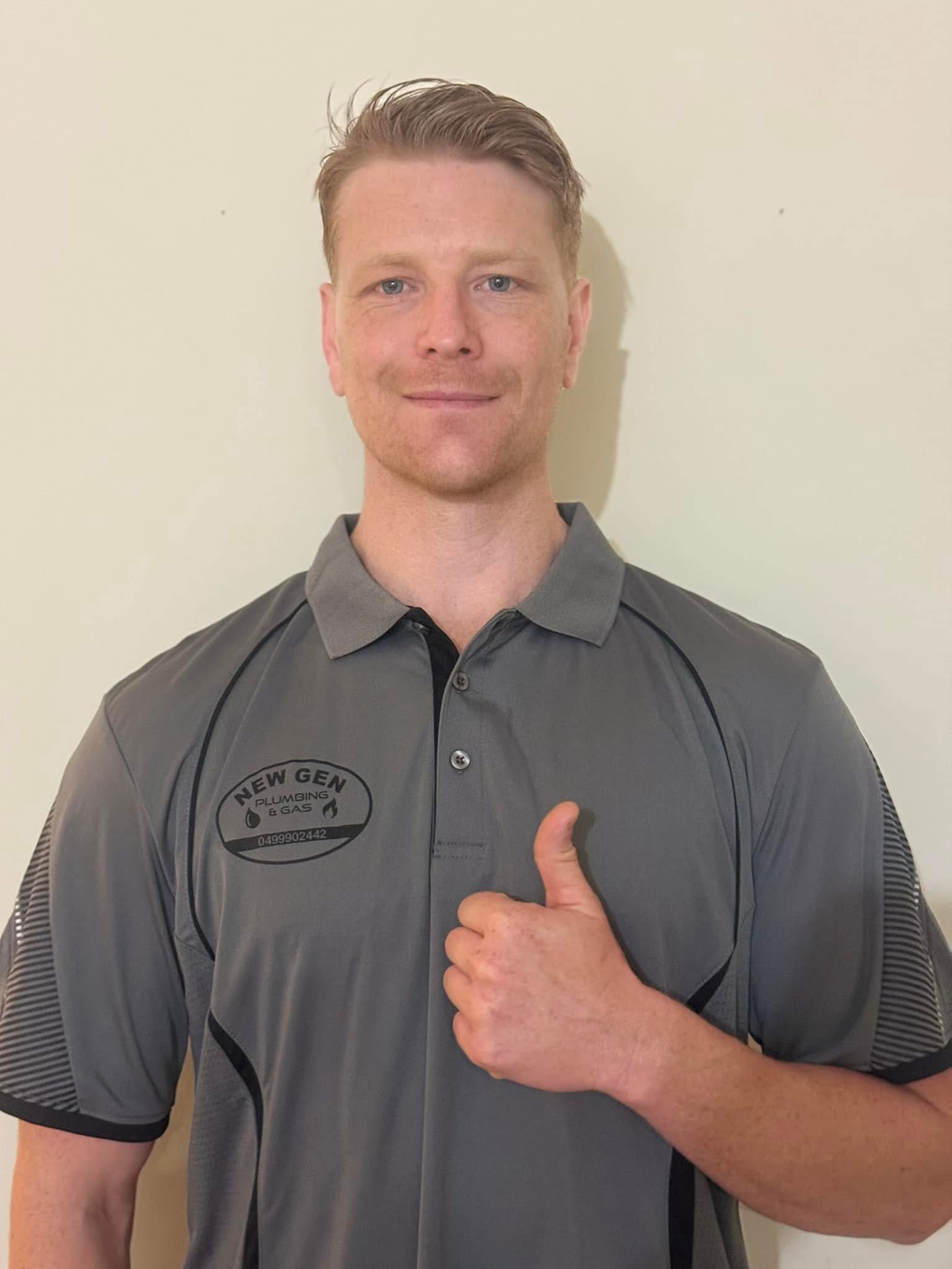 Man in gray polo shirt giving a thumbs-up against a plain beige wall. — New Gen Plumbing and Gas in Coolangatta, NSW