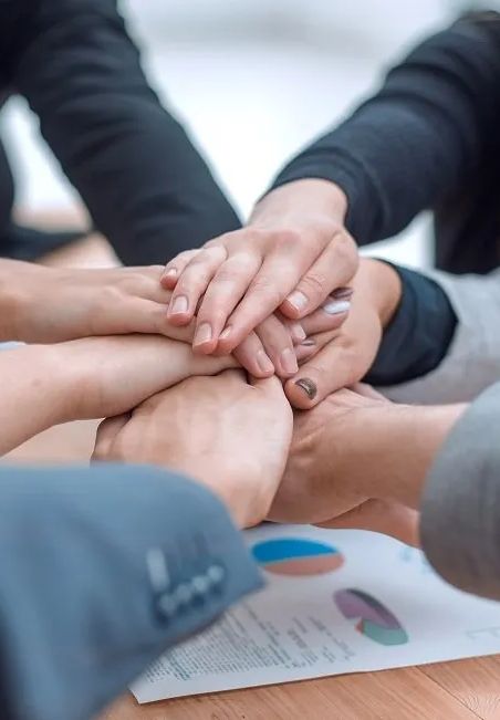A group of people are putting their hands together on a table.