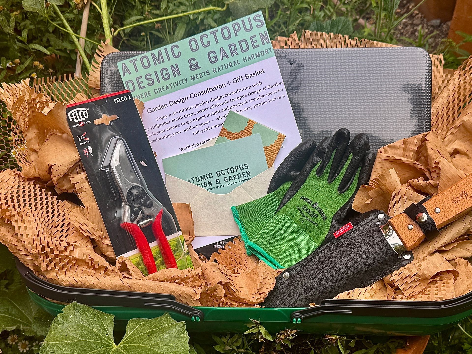 Gardening kit in a green container: clippers, gloves, trowel, instructions, and paper packaging.