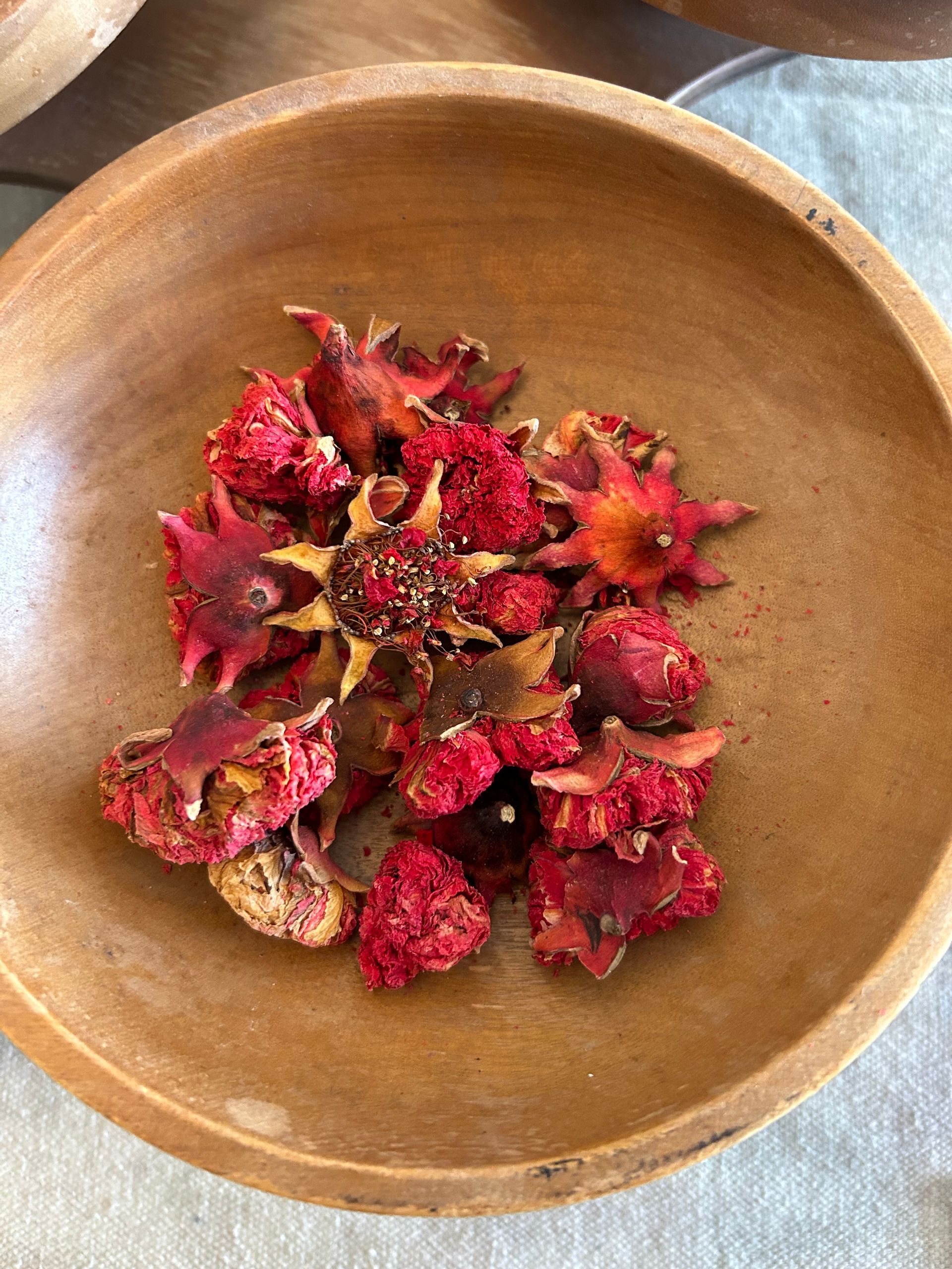 Dried red strawberry blossoms in a wooden bowl.