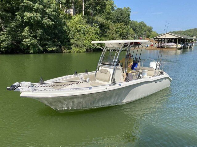 White motorboat cruising on green water near a tree-lined shore and dock