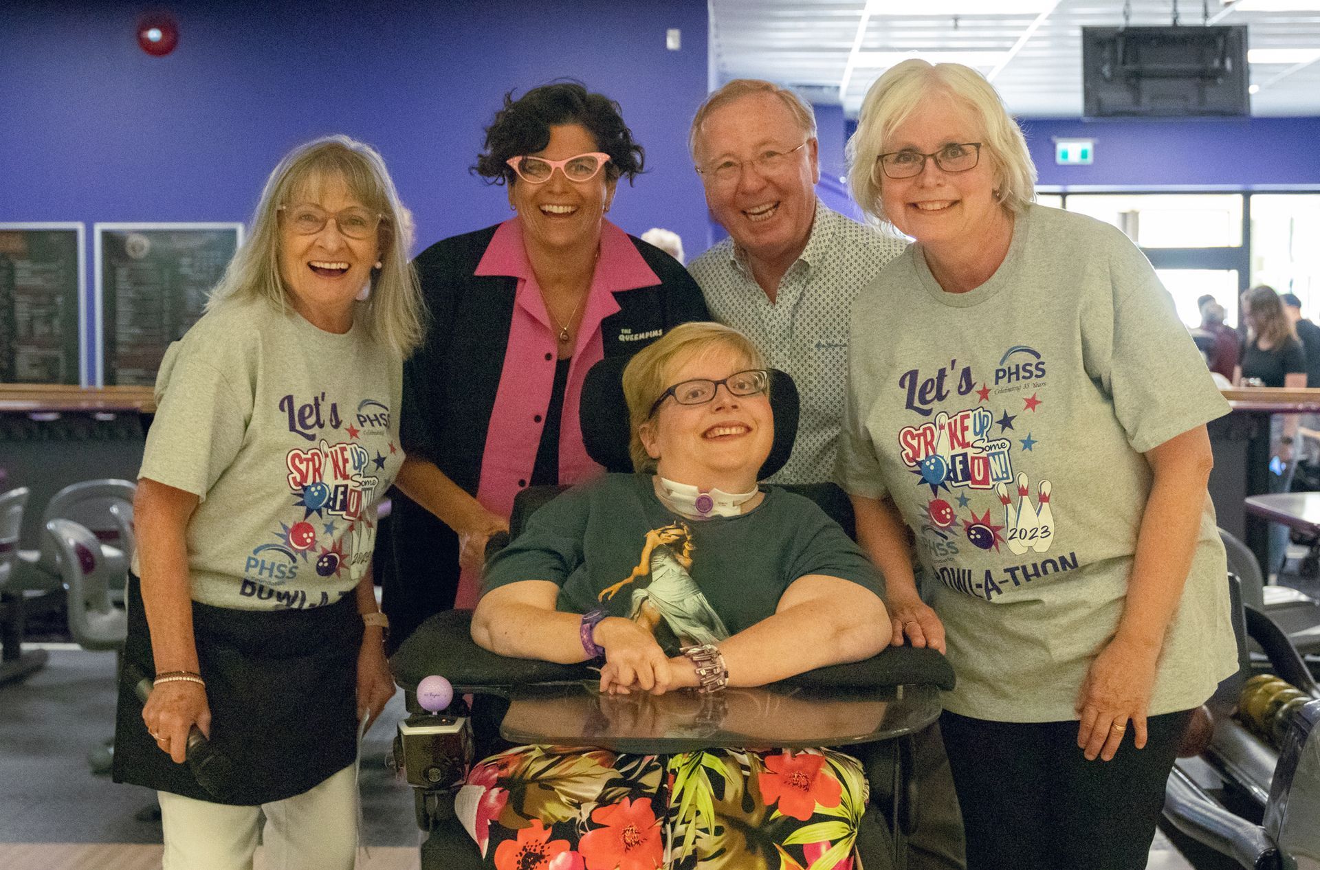A group of people are posing for a picture with a woman in a wheelchair.
