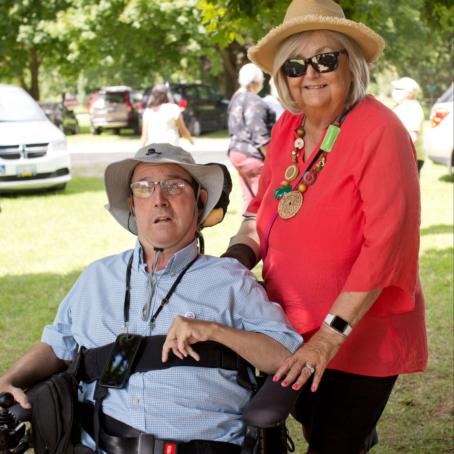 A woman in a red shirt is standing next to a man in a wheelchair