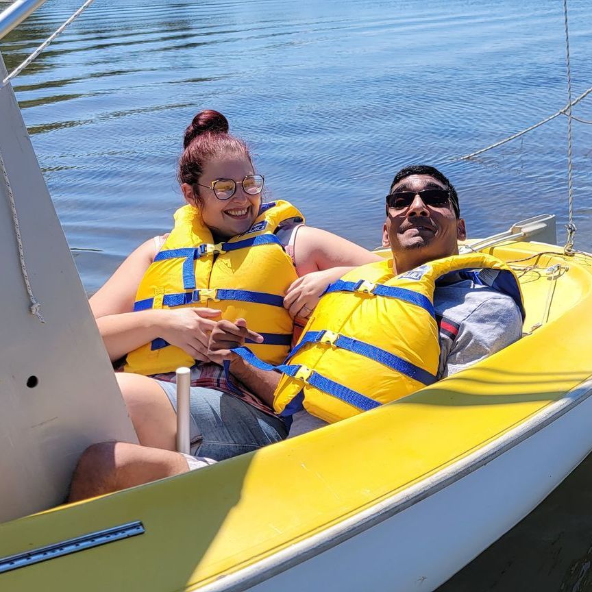 A man and a woman are sitting on a yellow boat in the water.