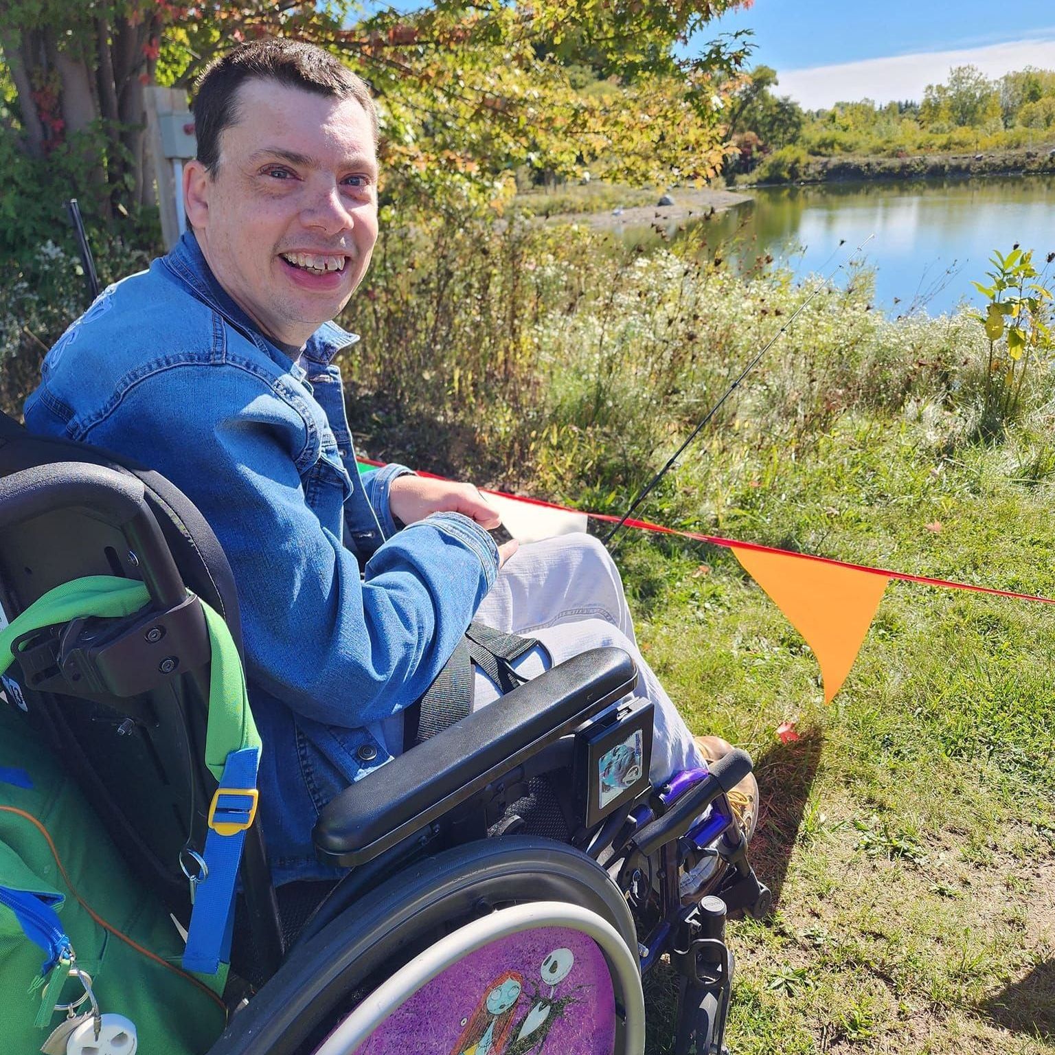 A man in a wheelchair is sitting in front of a lake.
