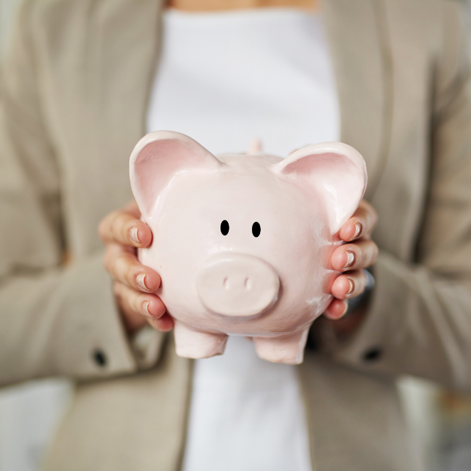 A woman is holding a pink piggy bank in her hands.