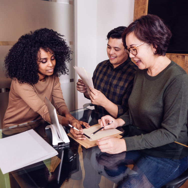 A group of people are sitting around a table looking at papers