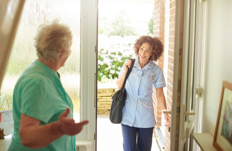 A nurse is talking to an elderly woman in a doorway.