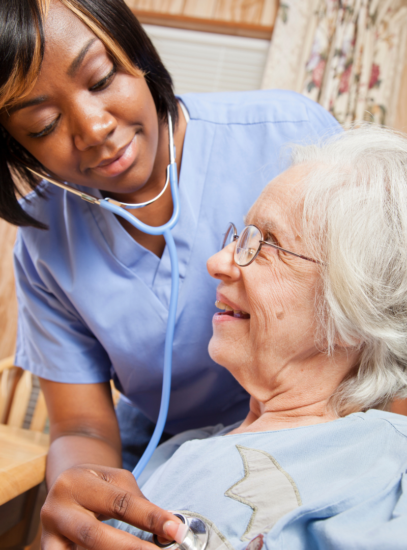 A nurse is listening to an elderly woman 's heartbeat with a stethoscope