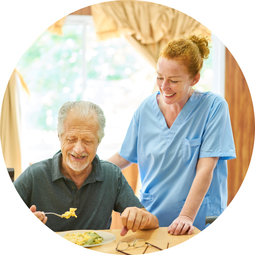 A nurse is helping an elderly man eat a meal