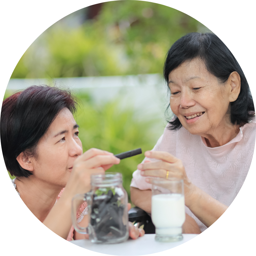 Two women are sitting at a table drinking milk from a mason jar.