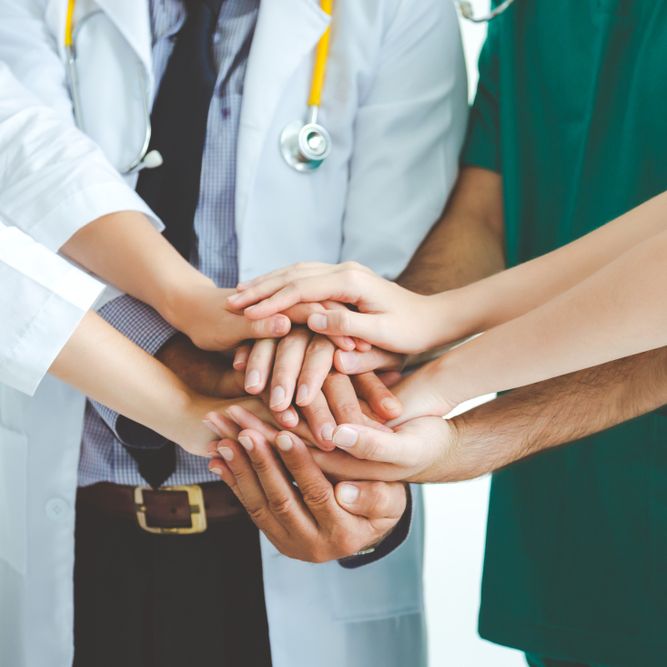 A group of doctors and nurses putting their hands together