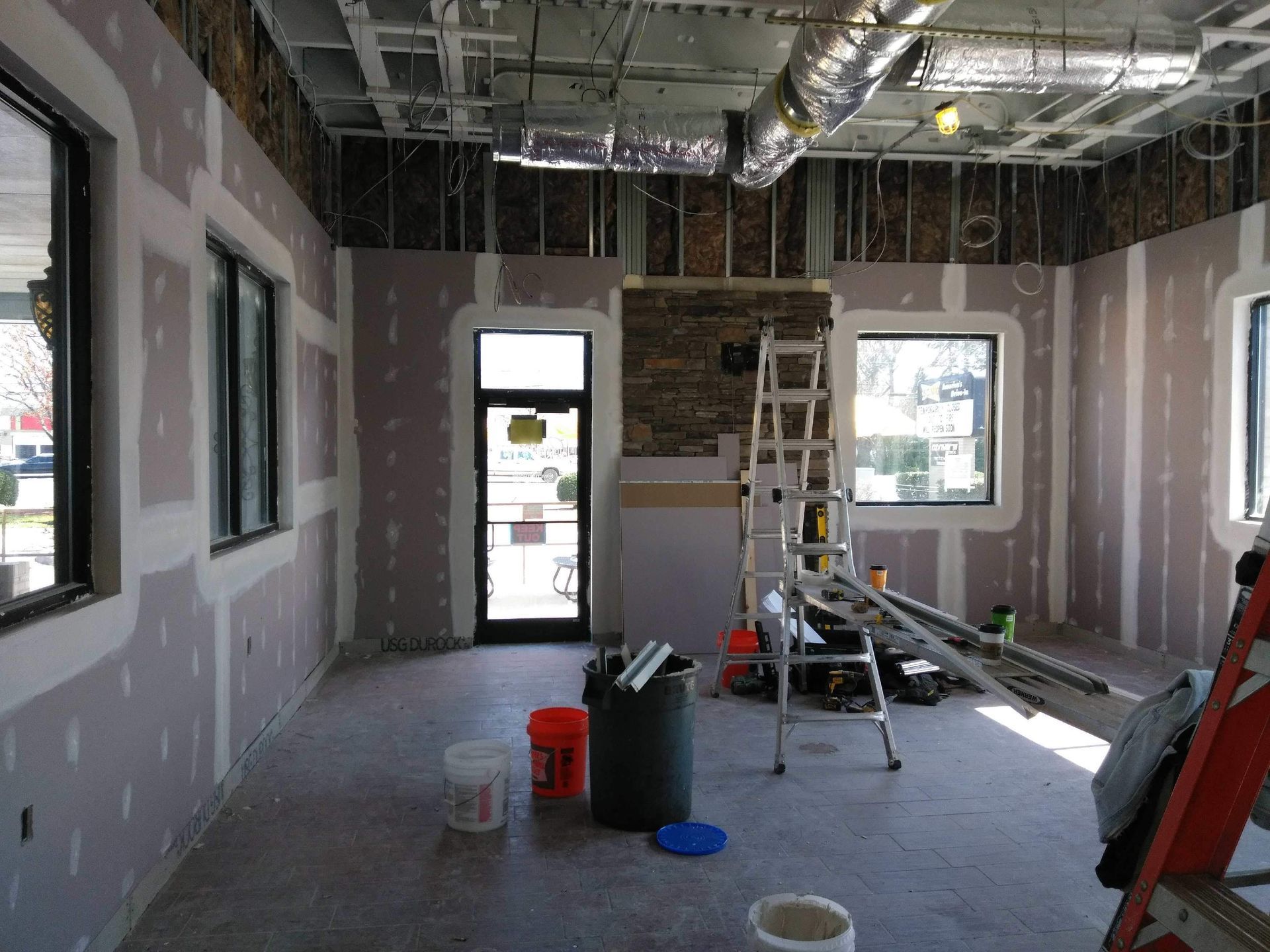 An empty room with a ladder and buckets in it