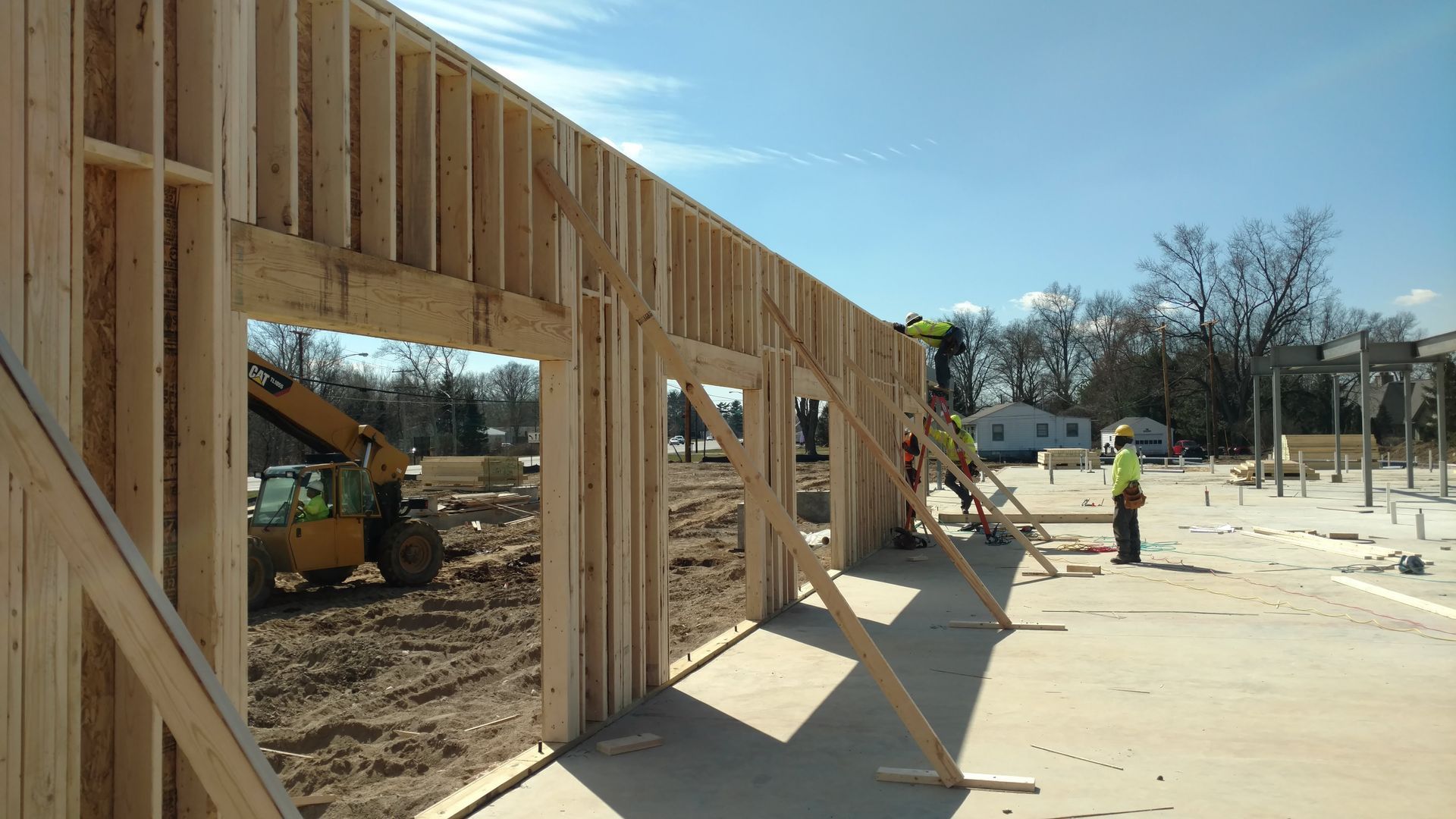 A large wooden wall is being built on a construction site.