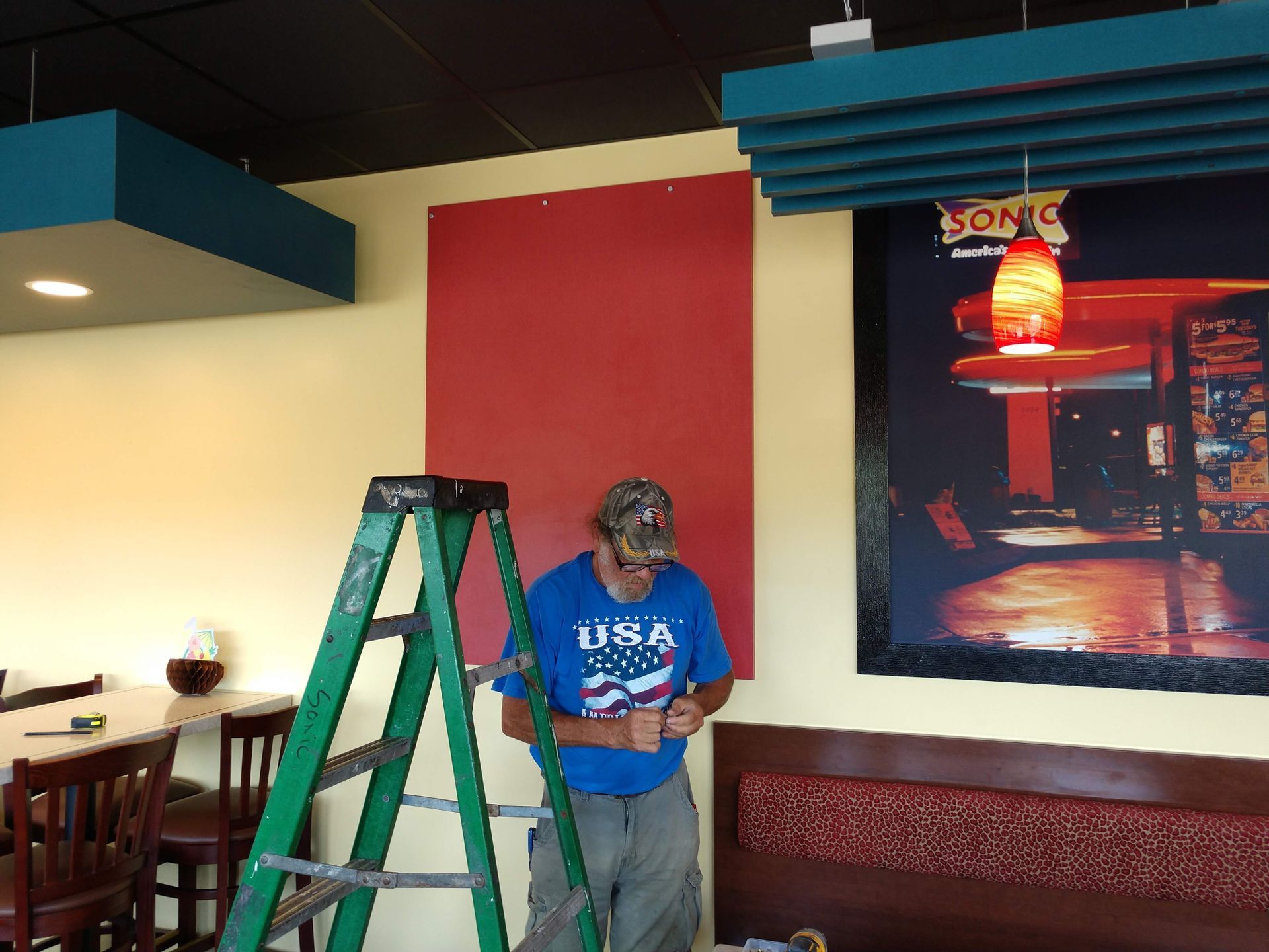 A man standing on a ladder wearing a usa shirt